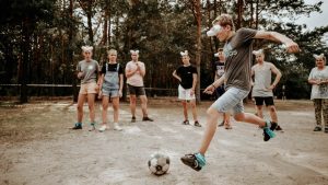 Teenagers enjoying an outdoor soccer game with a humorous twist using eyecovers as a challenge.